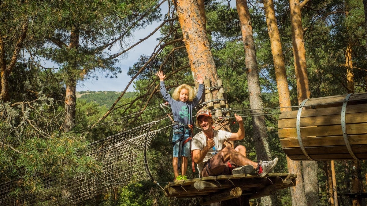 Father and child embrace adventure on a forest zipline in Cercedilla, Spain.
